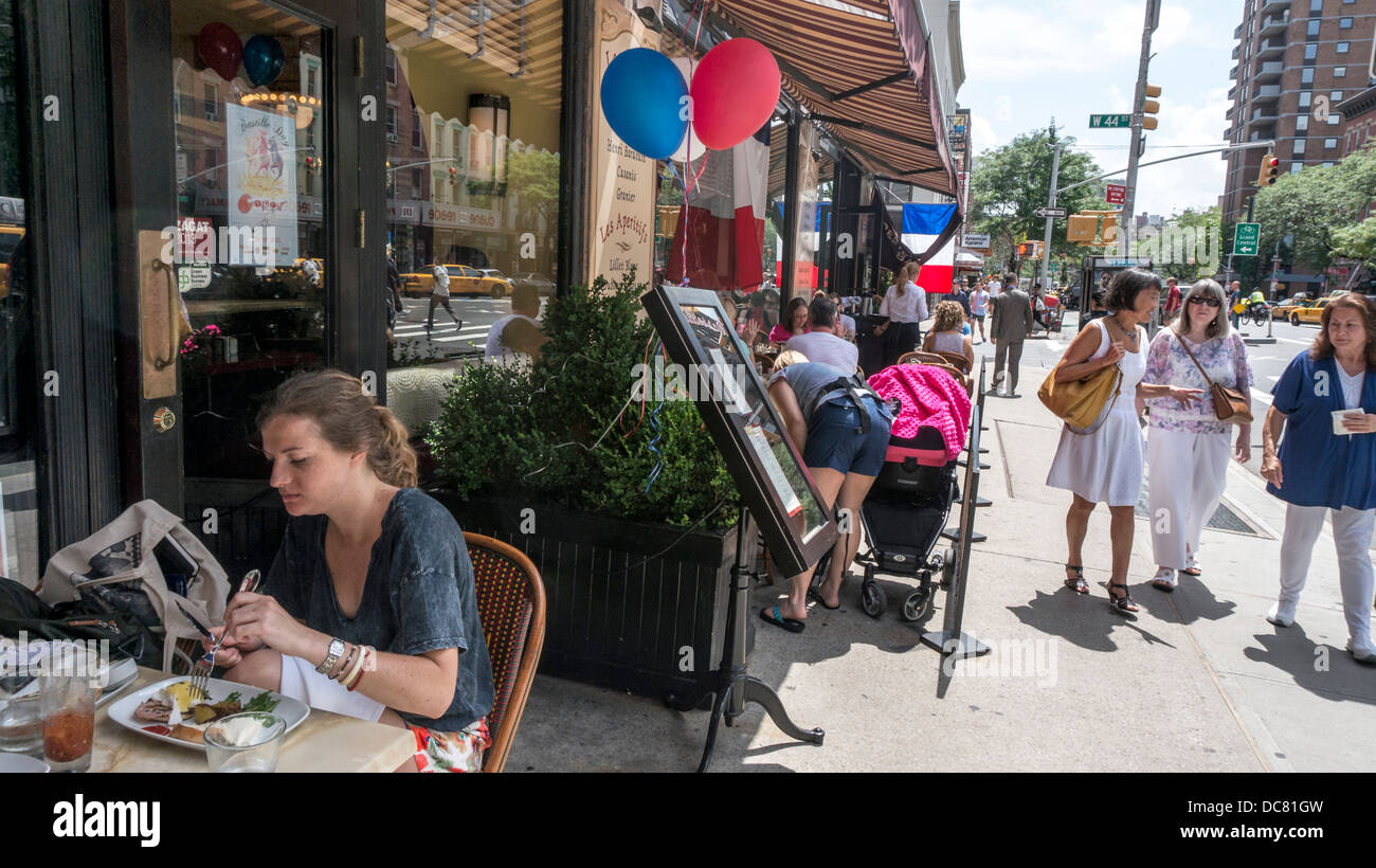 Ballons tricolores & drapeaux français décorer restaurant pour le jour de la Bastille en tant que jeune femme bénéficie d'un brunch à l'extérieur des oeufs Bénédictine Banque D'Images