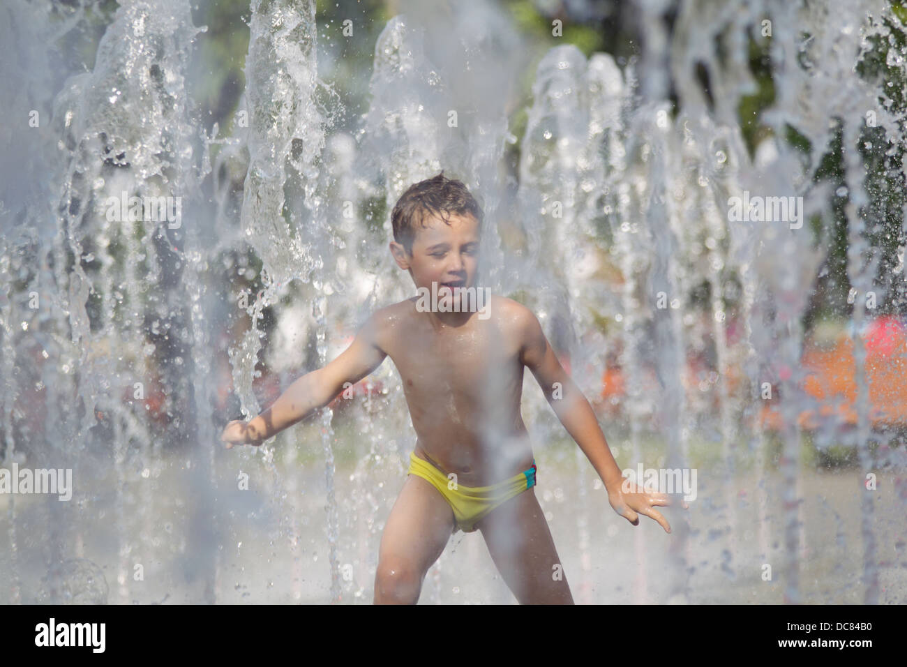 Enfant jouant dans une comédie musicale en fountainin une journée très chaude en été, dans la ville de Bucarest. Banque D'Images