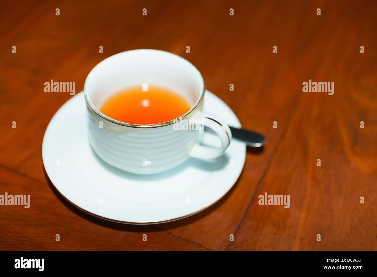 Tasse de thé sur la table en bois brun rouge dans le café. Selective focus sur le bord avant de la coupe. Banque D'Images