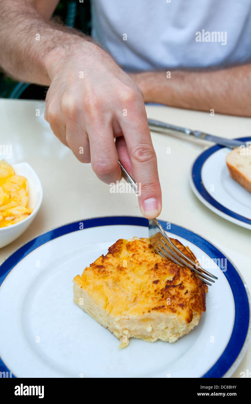 La main de l'homme la coupe une partie de l'omelette espagnole dans une terrasse. Madrid, Espagne. Banque D'Images