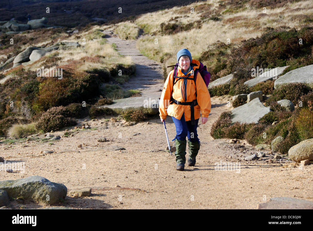 Femme walker en vêtements d'hiver marche sur Pennine Way, sur l'extrémité sud de Kinder Scout, Derbyshire Peak District, UK Banque D'Images