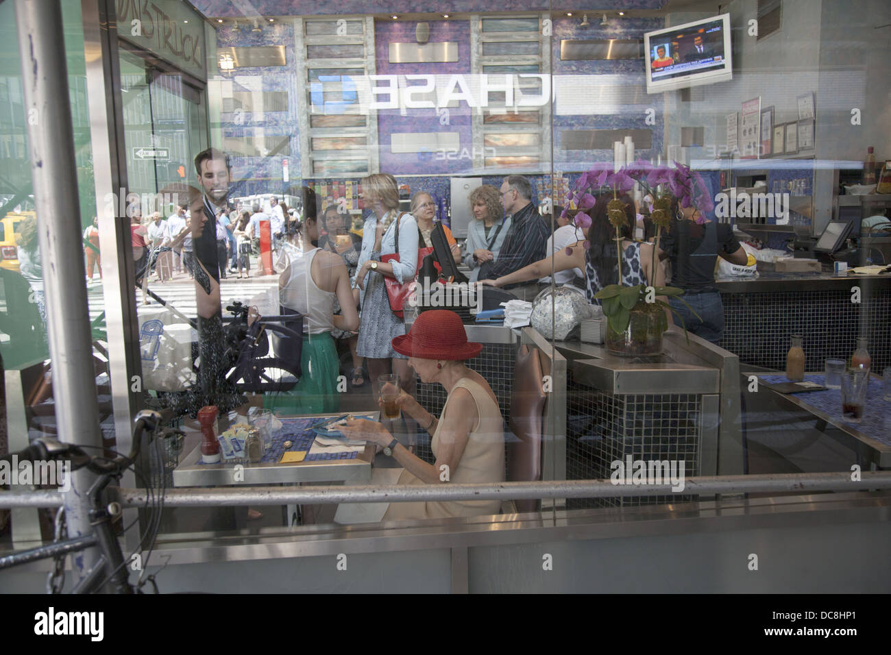 Les gens s'arrêtent pour une bouchée de déjeuner au milieu du chaos organisé de midtown Manhattan, New York. Banque D'Images