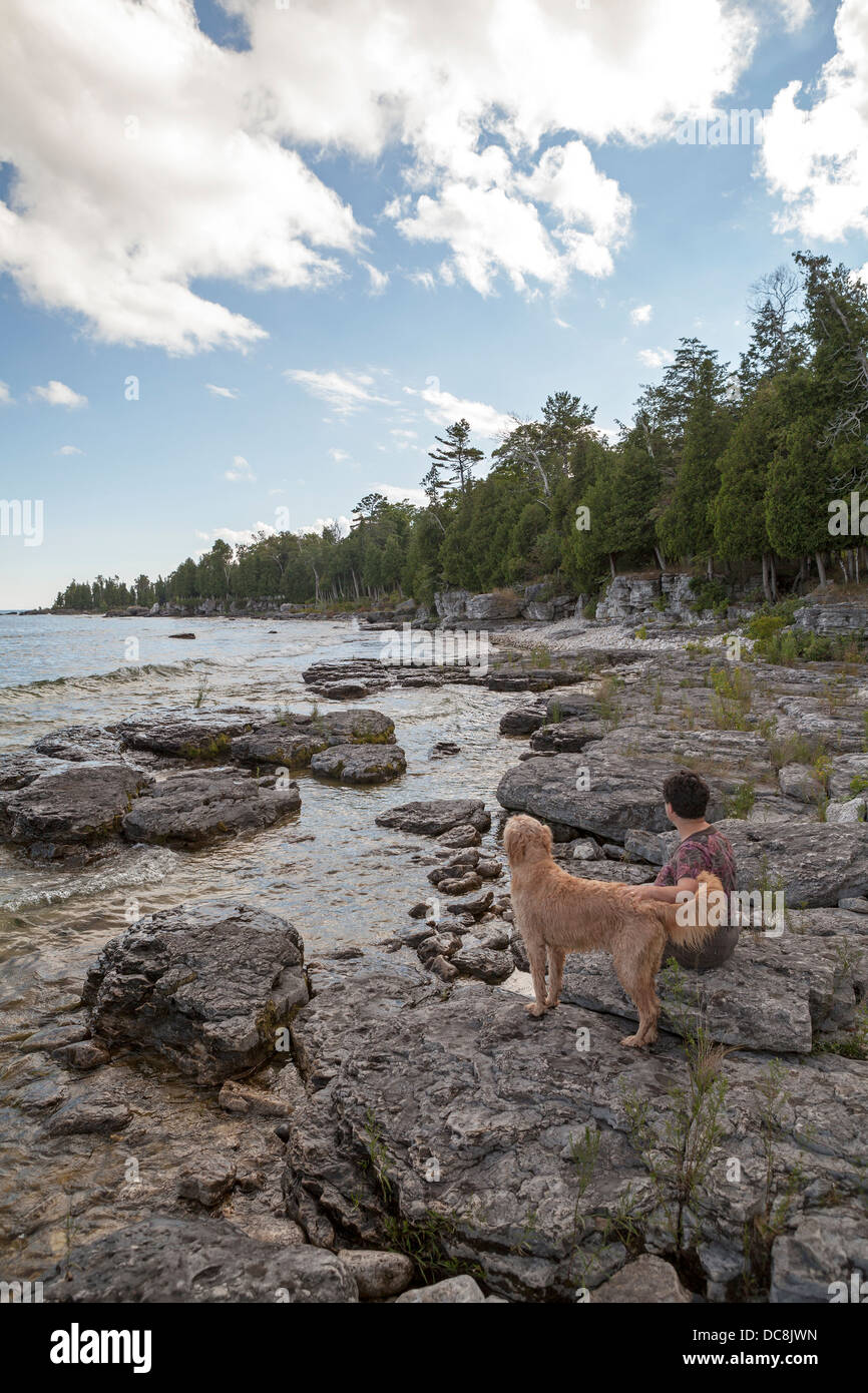 Une femme et son chien partagent un moment de calme au bord du lac Michigan sur l'île de Washington, du Wisconsin. Banque D'Images