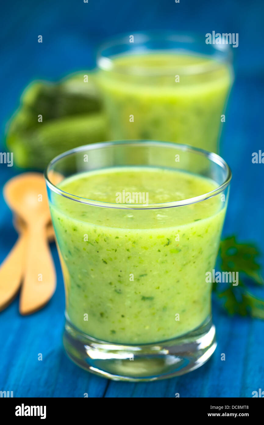 Soupe crème de courgettes servi en verres sur bois bleu avec une cuillère de bois, le persil et petite courgette Banque D'Images