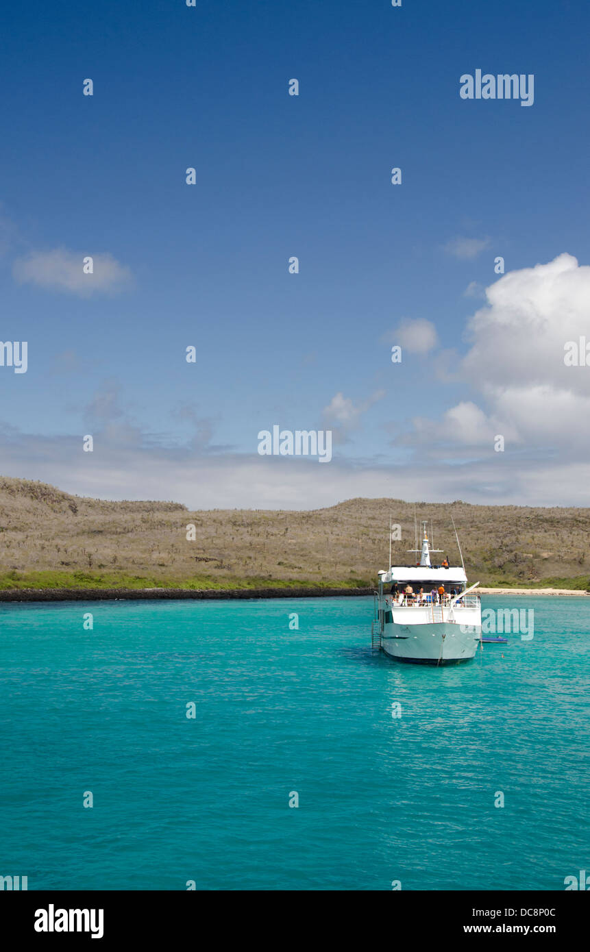 L'Equateur, Galapagos, Santa Fe, de la Baie de Barrington. Clear blue bay avec yacht touristique le long de la côte de l'île de Santa Fe. Banque D'Images