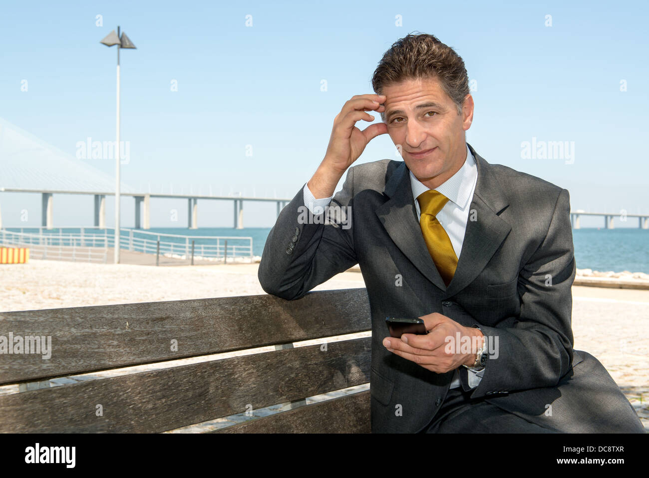 Inquiets businessman in a park bench with cellphone Banque D'Images