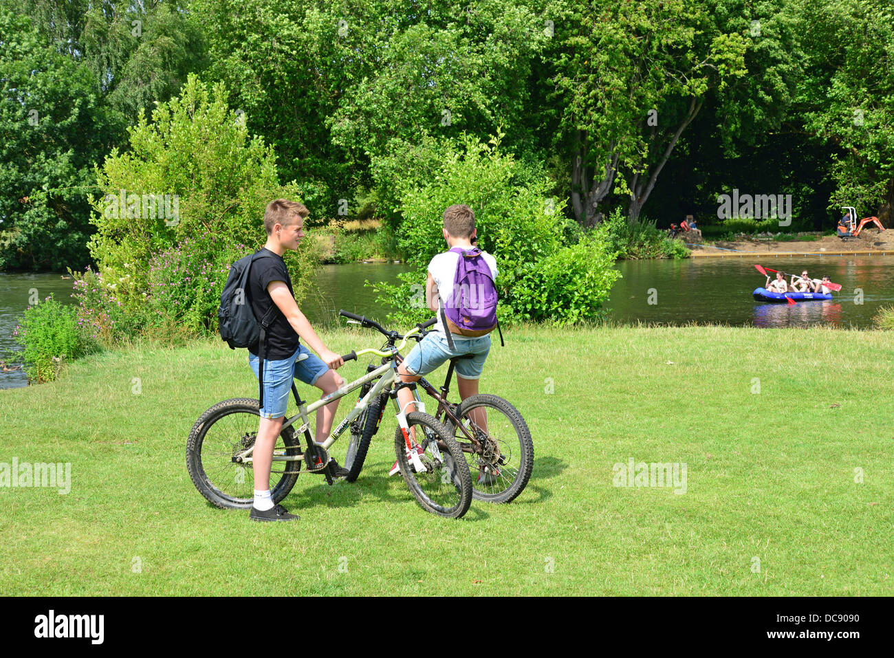 Les garçons sur les bicyclettes et les enfants du kayak sur la rivière Thames, Reading, Berkshire, Angleterre. United Kingdom Banque D'Images