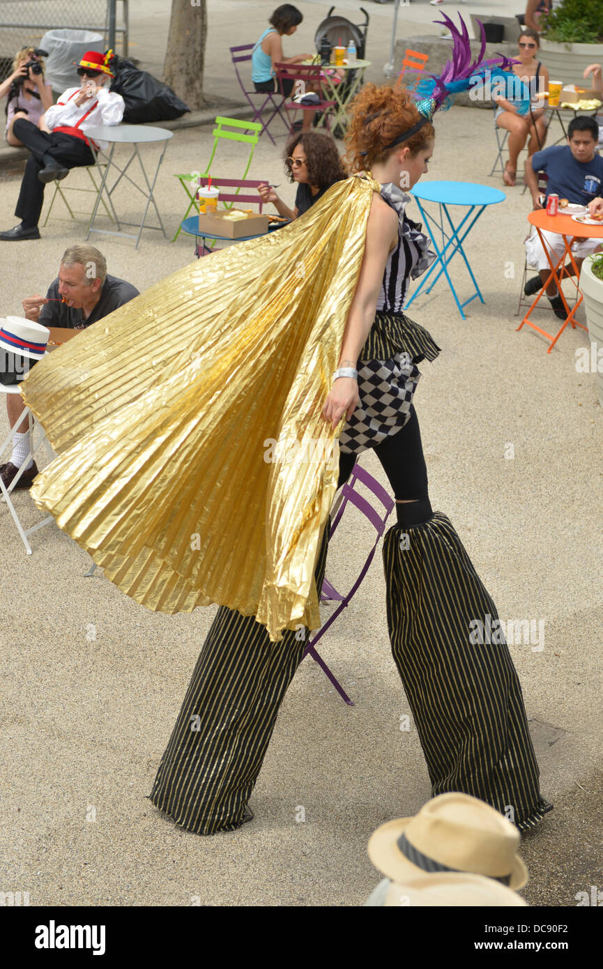 Brooklyn, New York, USA. 10 août 2013. À Coney Island, des Échasses KAE BURKE, Dame de cirque, porte une robe de soirée et costume cape d'or, haute comme elle marche sur des échasses, vu de dessus. Banque D'Images