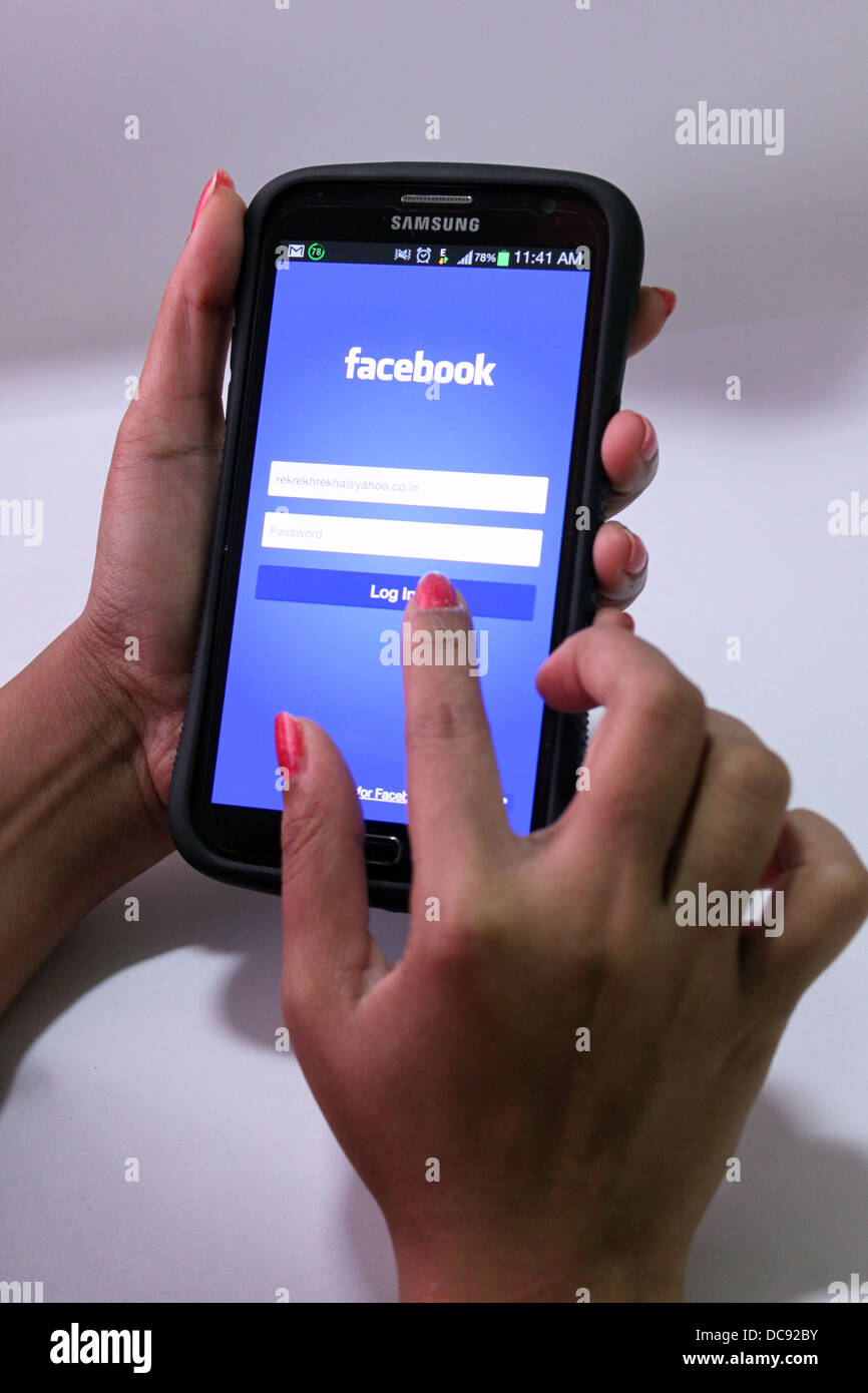 Femme de l'utilisation de Facebook sur un smartphone (samsung galaxy grand) Banque D'Images