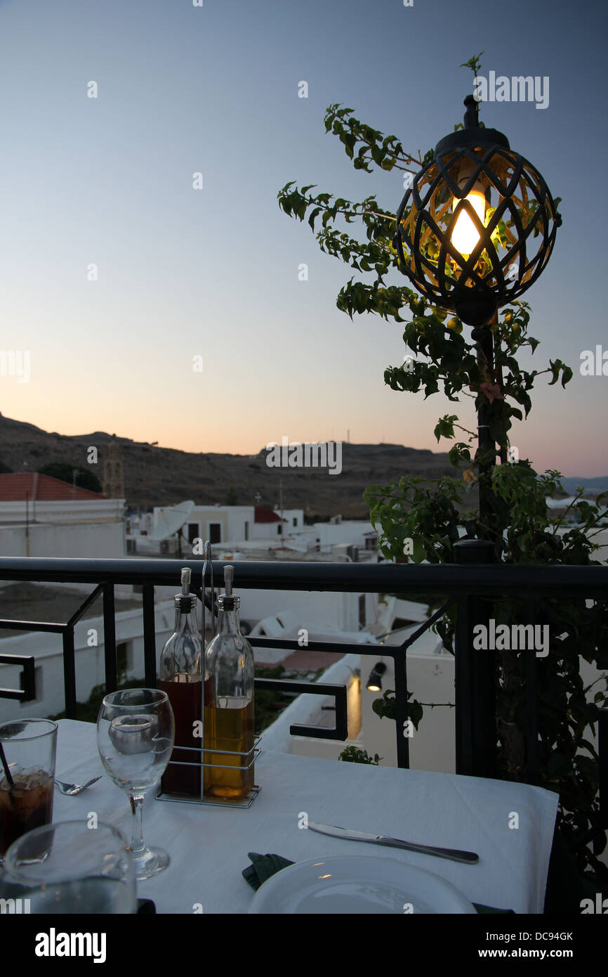 Vue sur Lindos, Rhodes, Grèce, du restaurant sur le toit au coucher du soleil, fermer sous le fort et de l'Acropole de Lindos. Banque D'Images