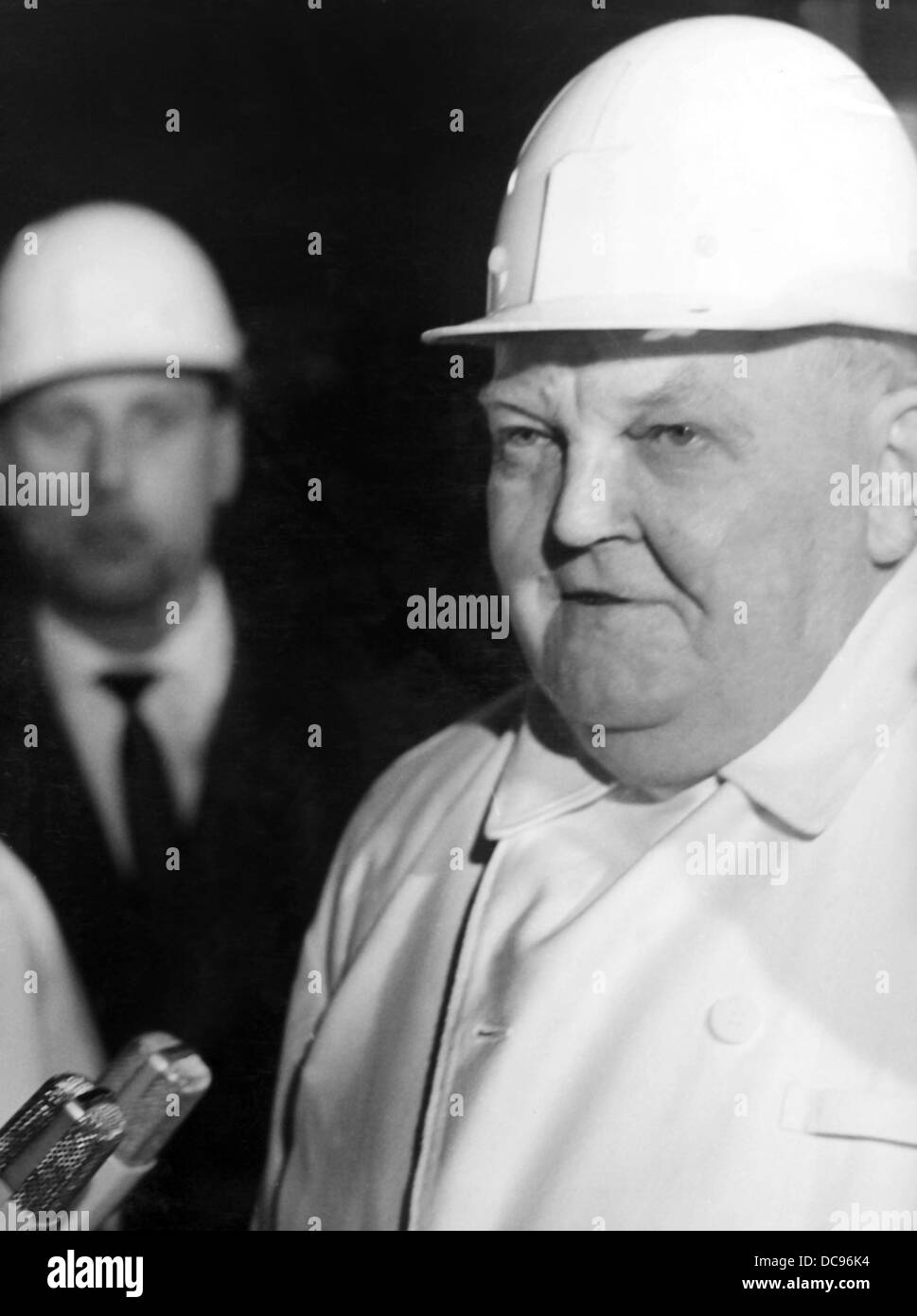 Chancelier Ludwig Erhard porte un casque de sécurité et les vêtements des mineurs pendant une visite à la mine de charbon dans la région de Herne le 2 avril en 1965. Banque D'Images