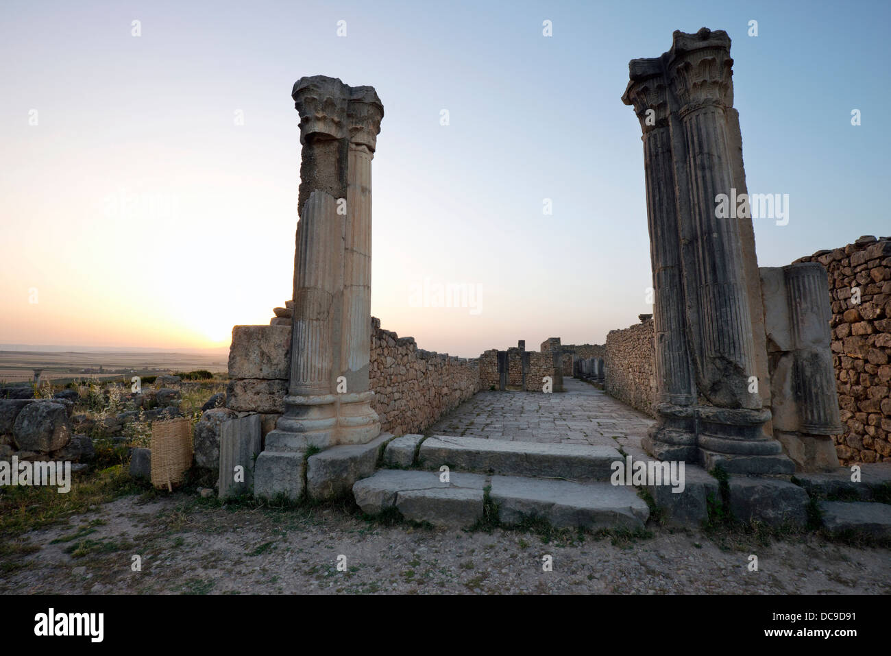 Ruines romaines au coucher du soleil au partiellement fouillé ville romaine de Volubilis, près de Meknes, Maroc. Banque D'Images