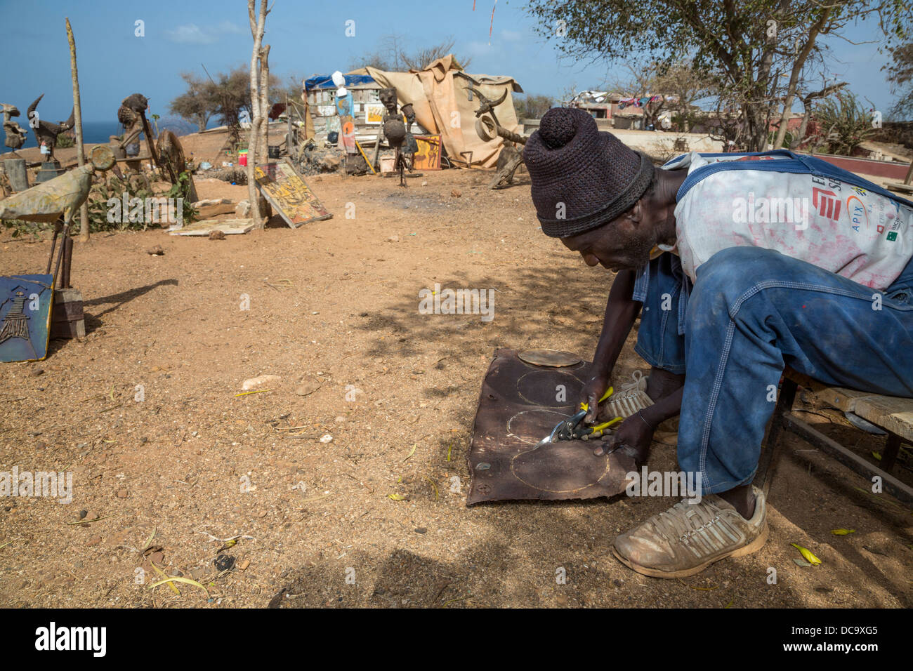 Artiste Amadou Dieng démontrant comment il travaille avec des objets trouvés et récupérés pour faire ses constructions. L'île de Gorée au Sénégal. Banque D'Images