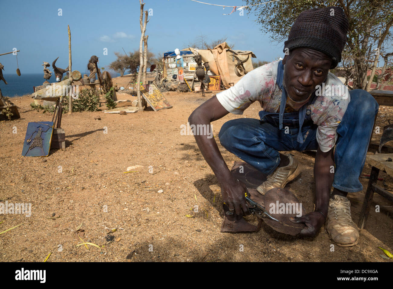 Artiste Amadou Dieng démontrant comment il travaille avec des objets trouvés et récupérés pour faire ses constructions. L'île de Gorée au Sénégal. Banque D'Images