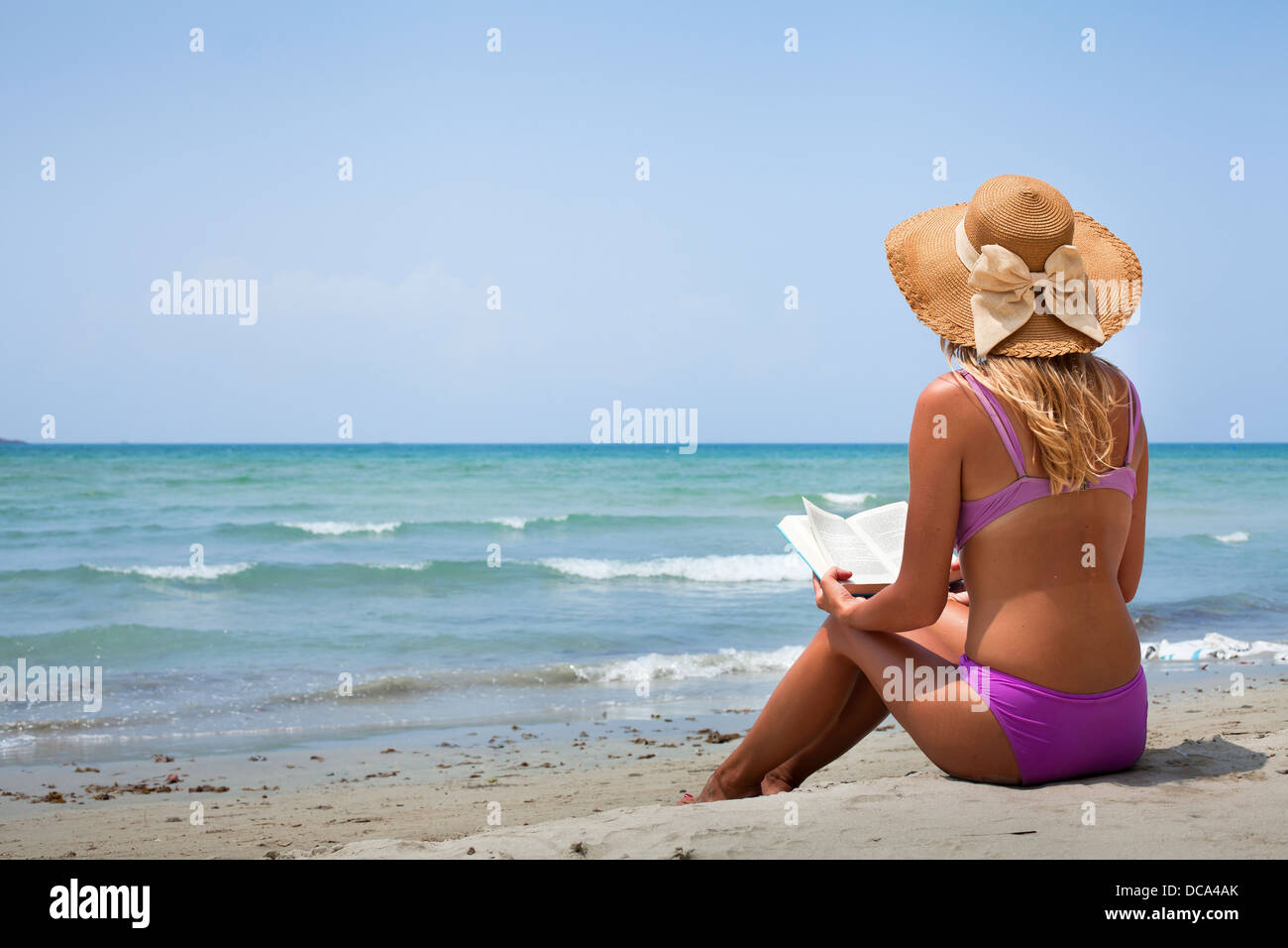 Woman in bikini lecture livre sur la plage Banque D'Images