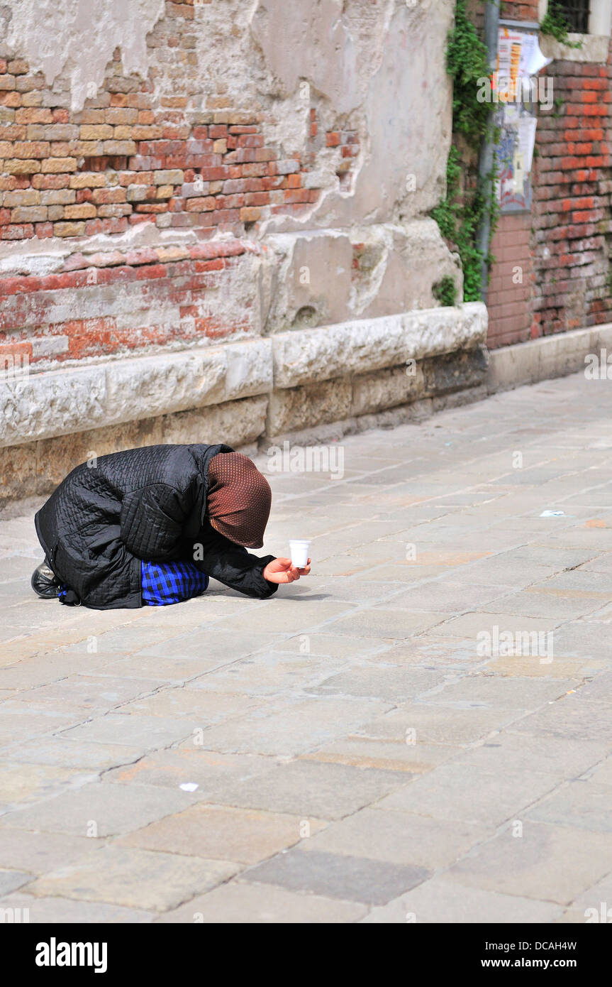 Femme nécessiteuse dans une rue de Venise avec un bras tendu tenant une tasse de mendicité pour passer des gens à offrir de l'argent, Italie Banque D'Images