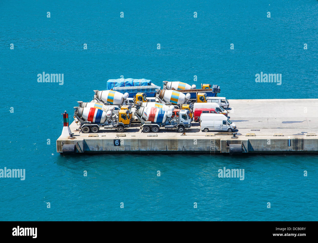 Lignes colorées de bétonnière camions garé sur une jetée en béton au-dessus de l'eau bleue Banque D'Images