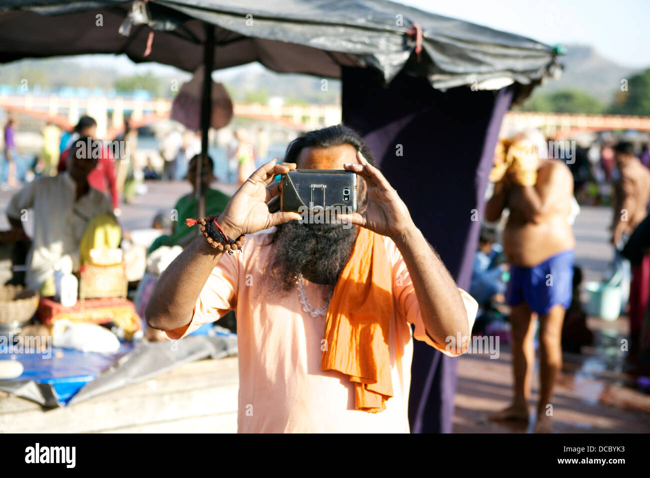 Un hindou sadhu prend une photo en utilisant son téléphone appareil photo à Haridwar, Inde. Banque D'Images