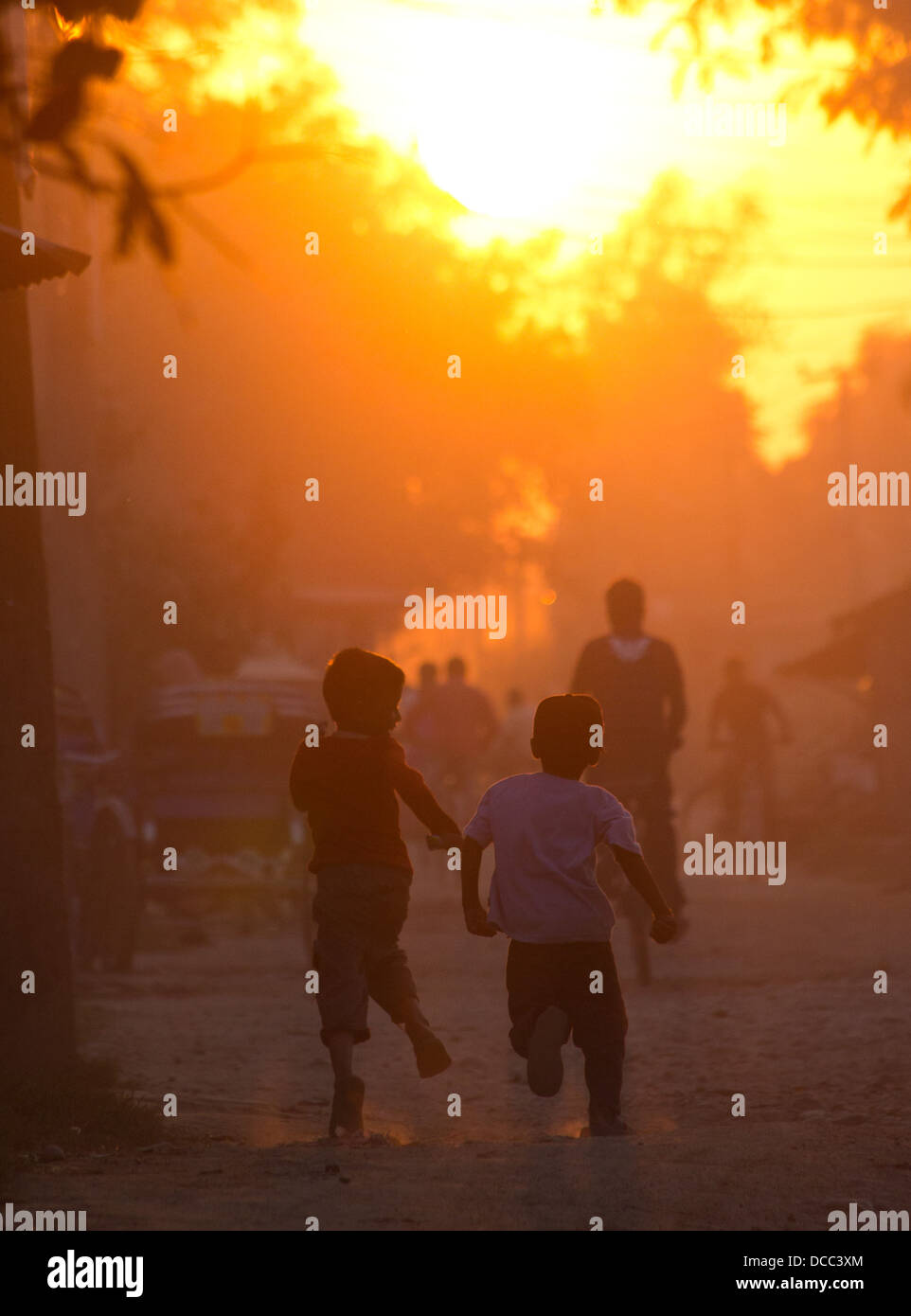 Deux garçons s'exécutant sur une rue au coucher du soleil, le Népal, Nepalganj Banque D'Images