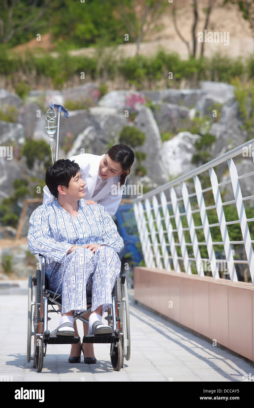 Une femme médecin derrière un patient avec une chaise roulante Banque D'Images