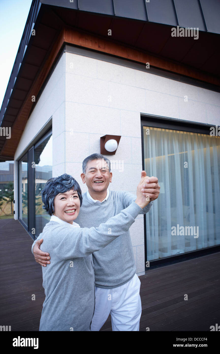 Middle aged couple dancing in front of a house Banque D'Images