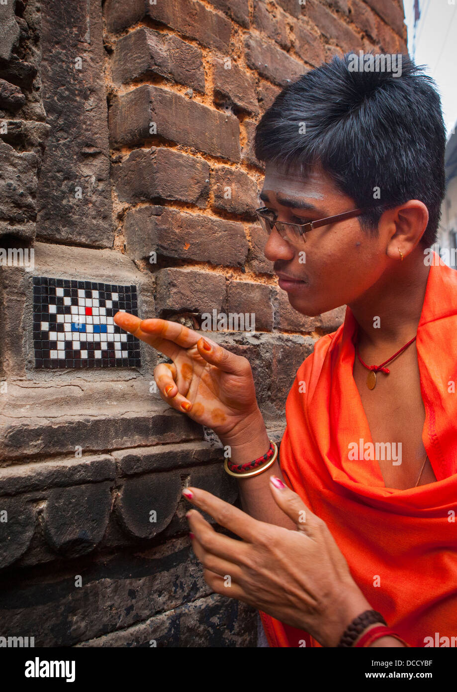 Indien à la recherche à une mosaïque Space Invader dans la rue, Varanasi, Inde Banque D'Images