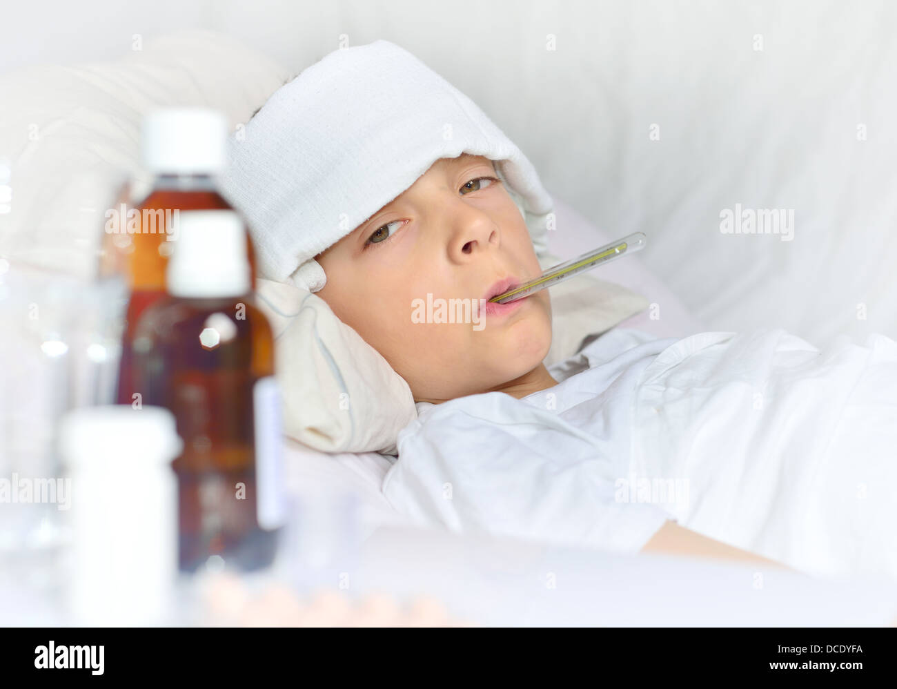 Garçon malade au lit avec une compresse et thermomètre Banque D'Images