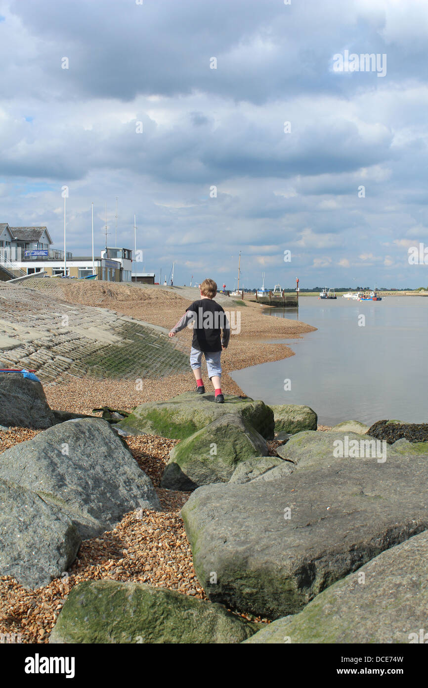 Jeune garçon climing à travers des roches à l'estuaire d'Orwell, vieille Felixstowe, Suffolk Banque D'Images