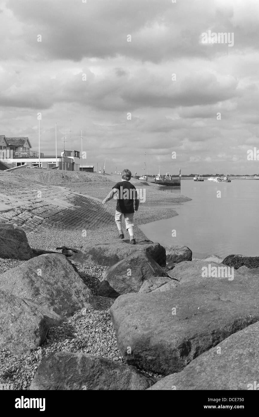 Garçon sur des pierres à l'estuaire d'Orwell, Suffolk Banque D'Images