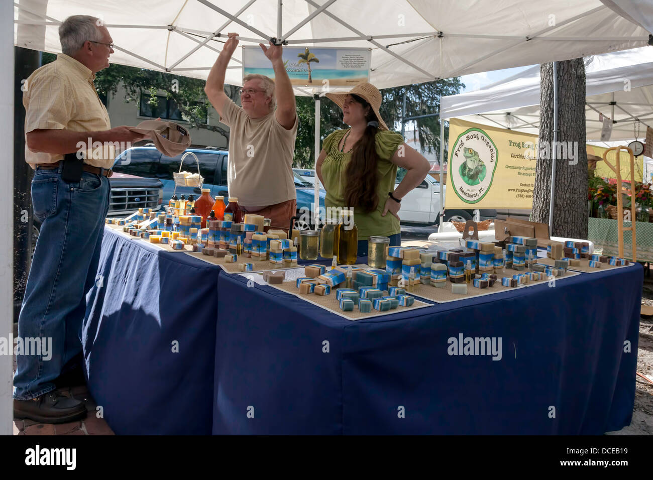 Deux vendeurs de parler avec le client à propos du savon fait main produits de farmer's market stall. Banque D'Images