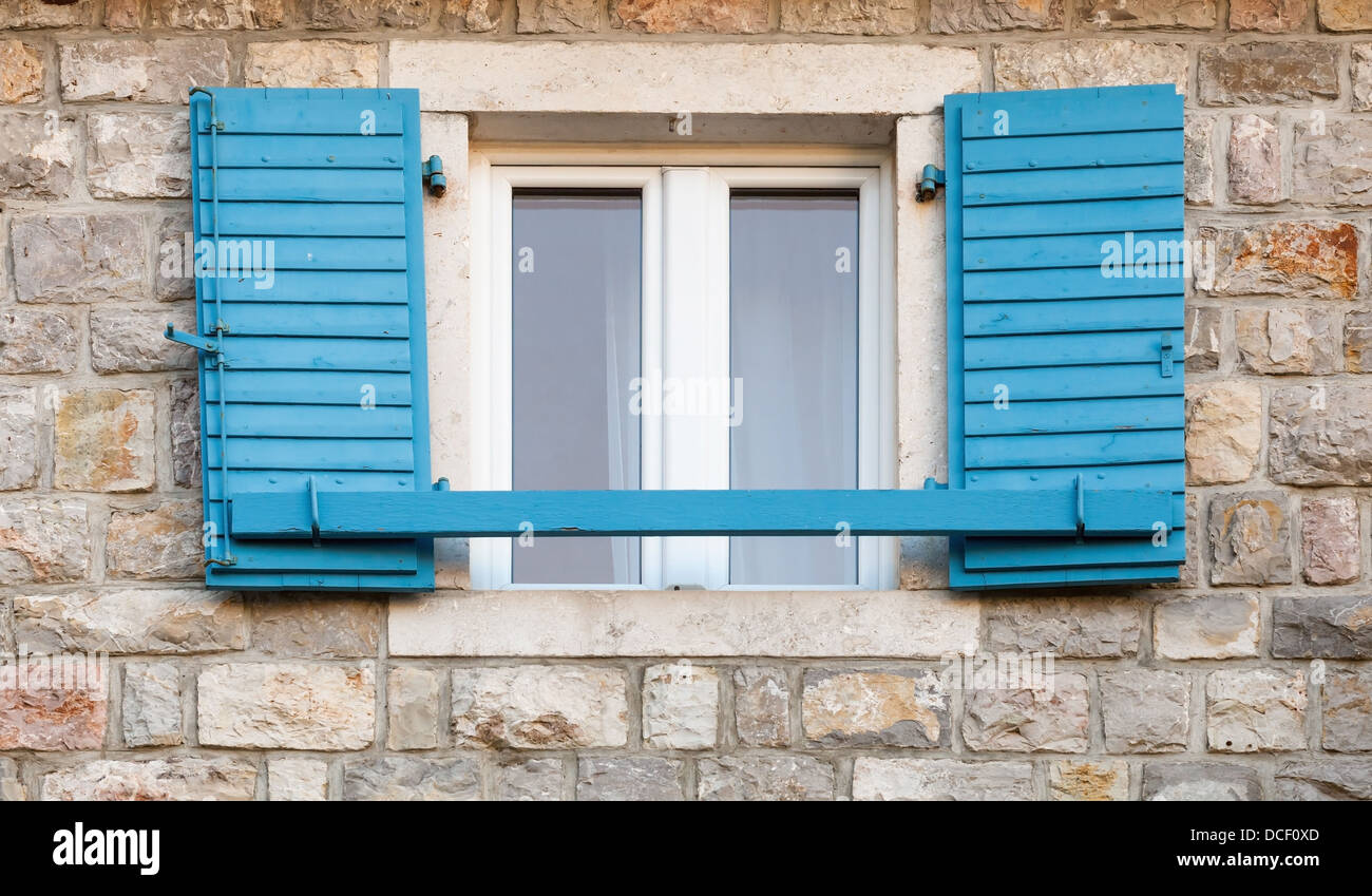 Fenêtre en bois bleu avec jalousies ouvert dans le vieux mur de pierre grise Banque D'Images