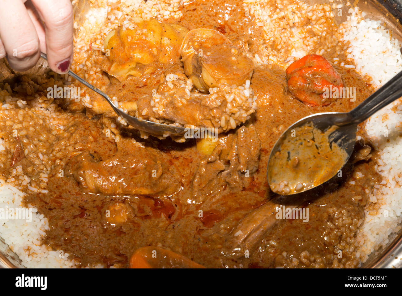 Ragoût de poulet aux noix de cajou, les poivrons, et le riz. Les gens autour de la table, mangent à partir d'un plat commun. La Gambie. Banque D'Images