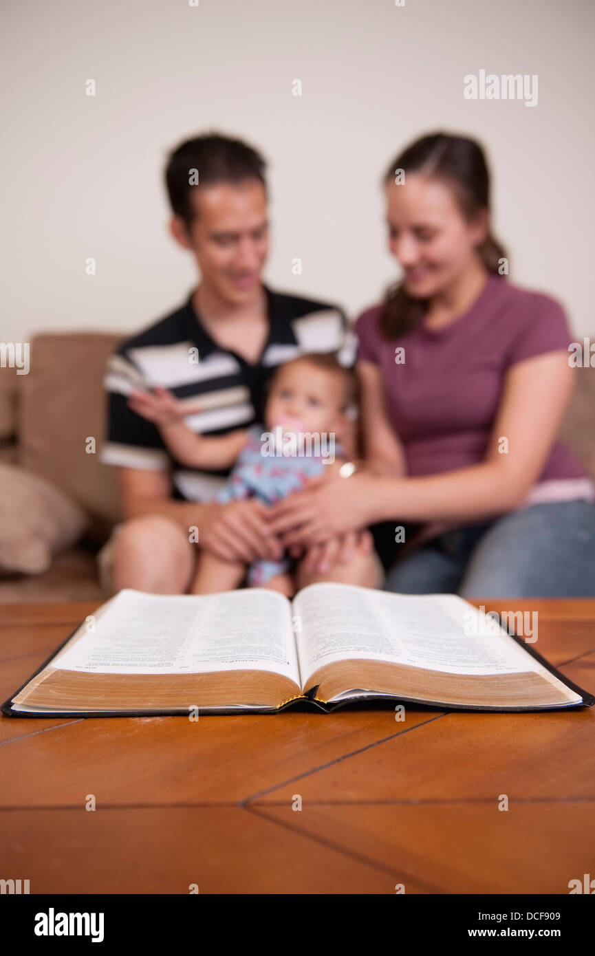 Une famille avec une Bible sur la table à café Banque D'Images