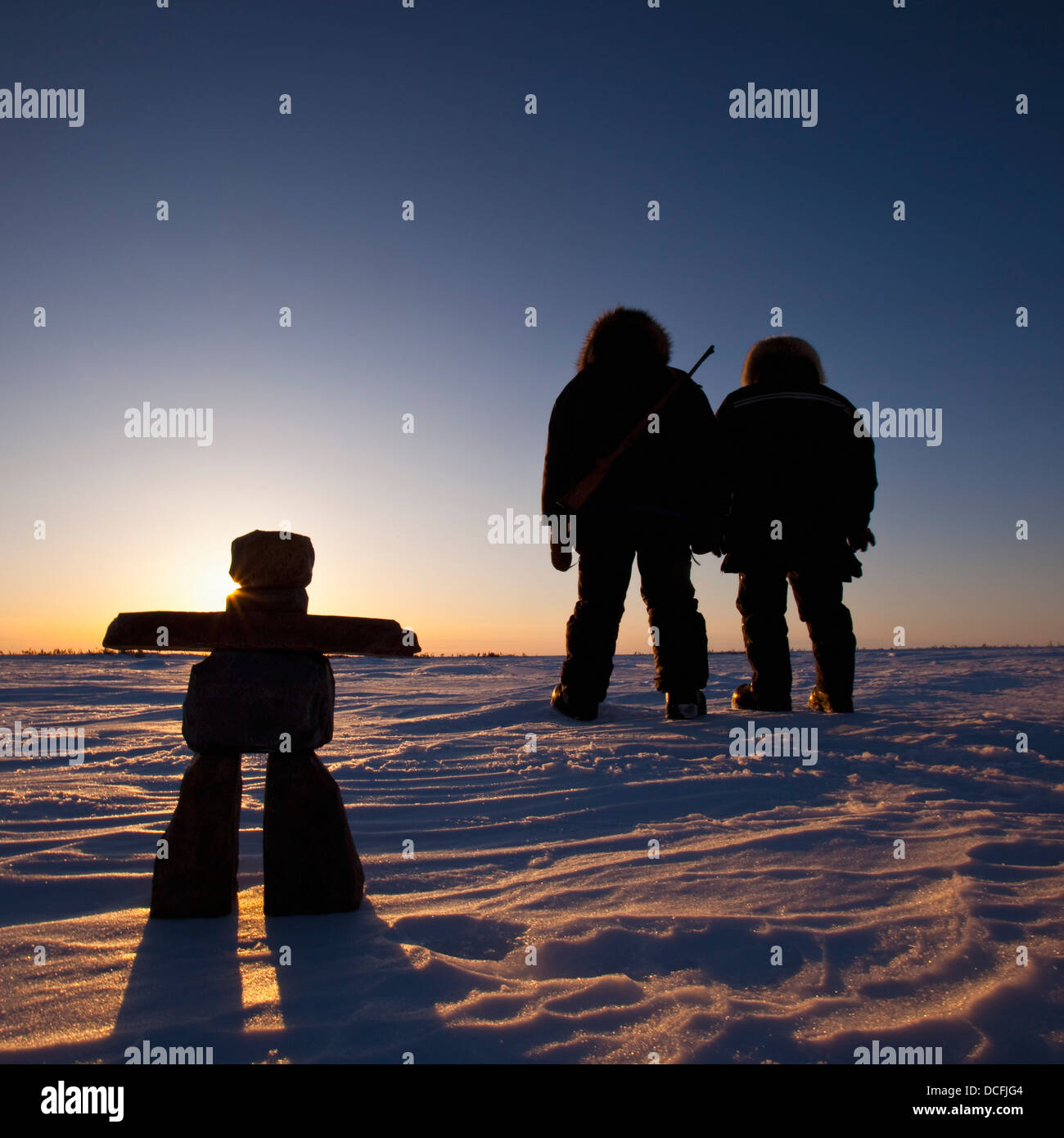 Silhouette de deux personnes (Chasseurs) Debout dans la neige en regardant le soleil se coucher dans le parc national ; Churchill, Manitoba Banque D'Images