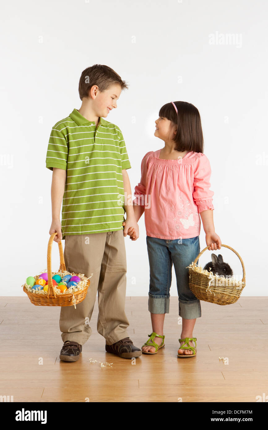 A Boy and Girl Holding paniers avec un lapin et les oeufs de Pâques colorés en eux ; Three Hills, Alberta, Canada Banque D'Images