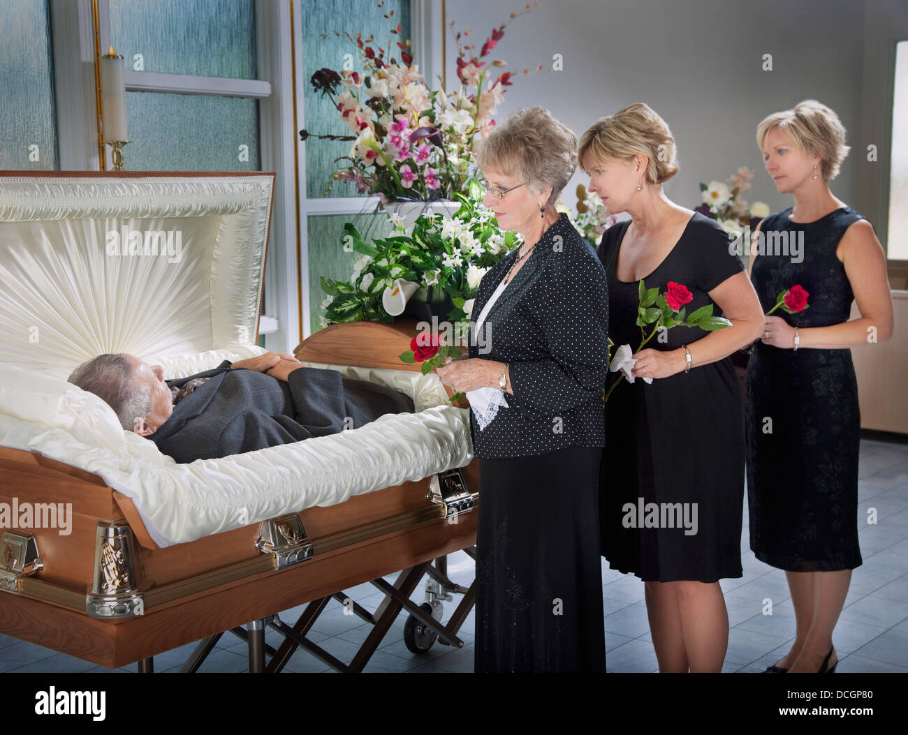 Trois femmes debout près du corps d'un homme portant dans un cercueil Banque D'Images