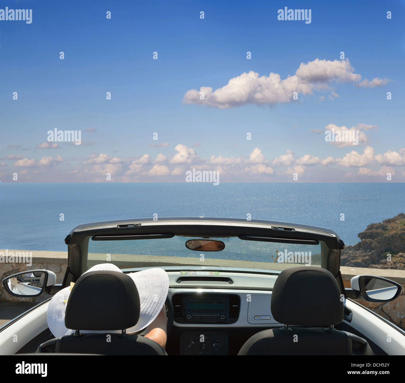 Woman in white hat dans une voiture ouverte avec une vue sur la mer Banque D'Images