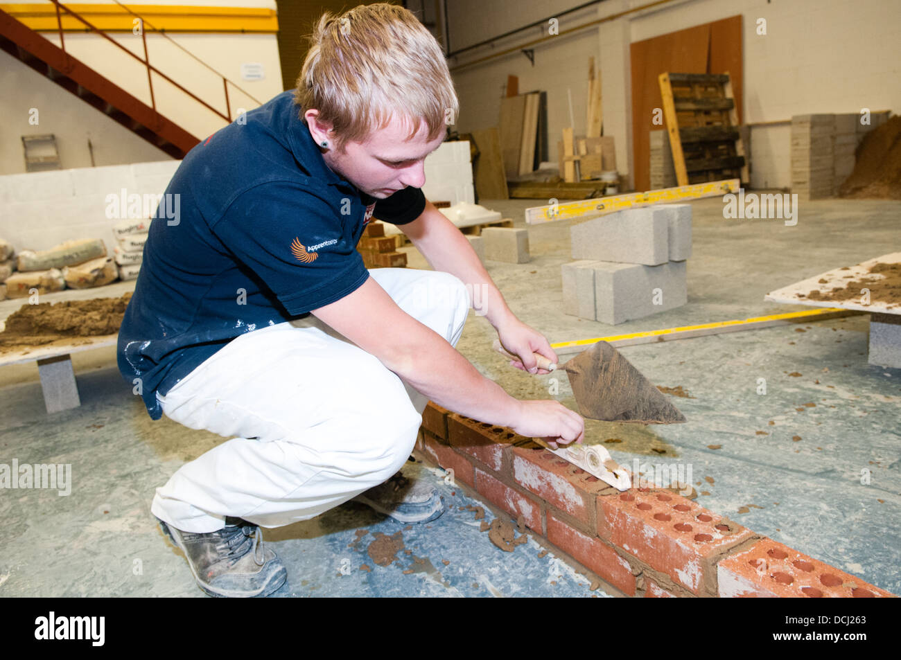 Blanc jeune apprenti bricklayer et platerer dans l'enseignement universitaire a métier qualifié Banque D'Images