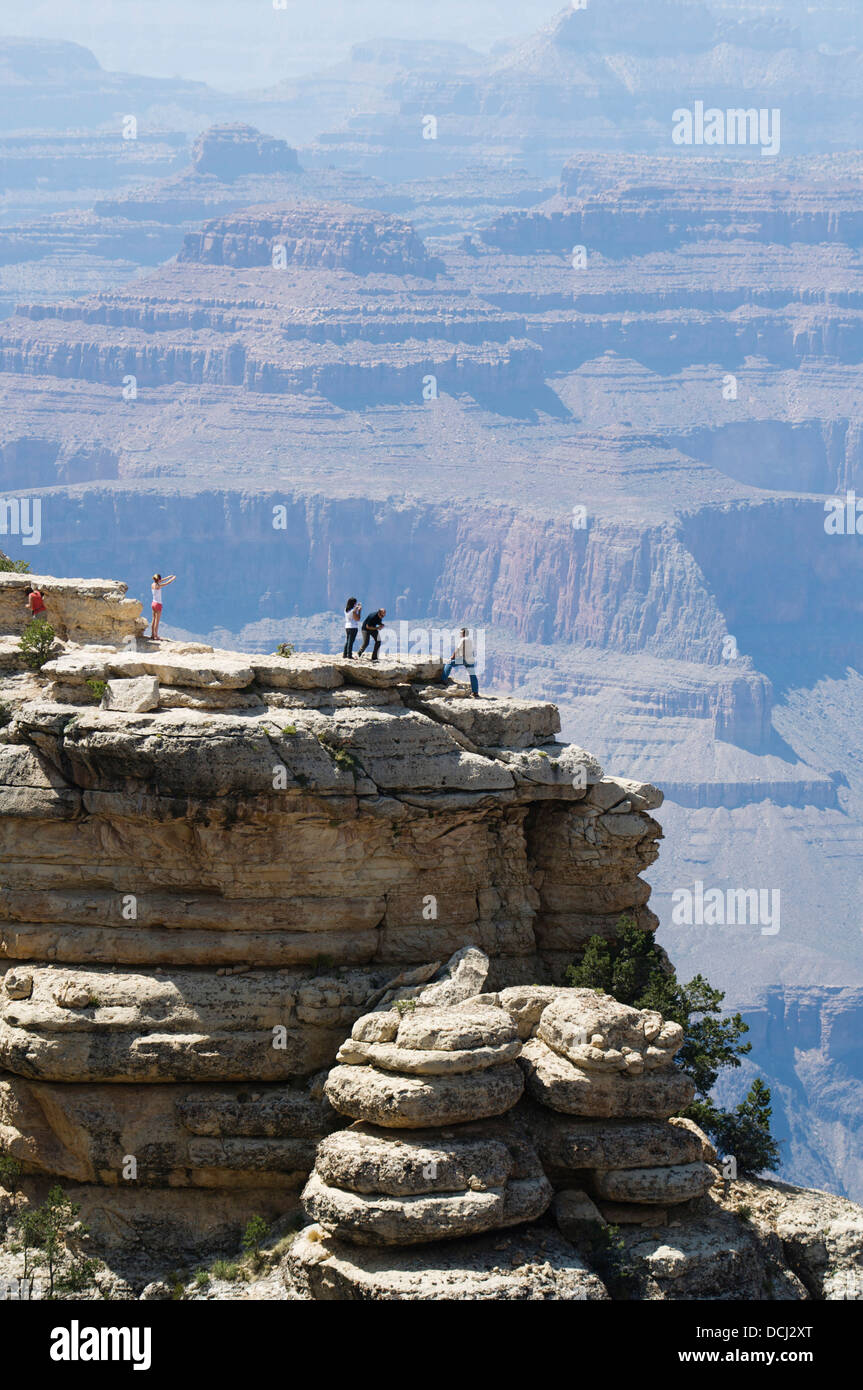 Les personnes qui se font passer pour des photos sur un affleurement rocheux avec le Grand Canyon, Arizona, en toile de fond. Banque D'Images