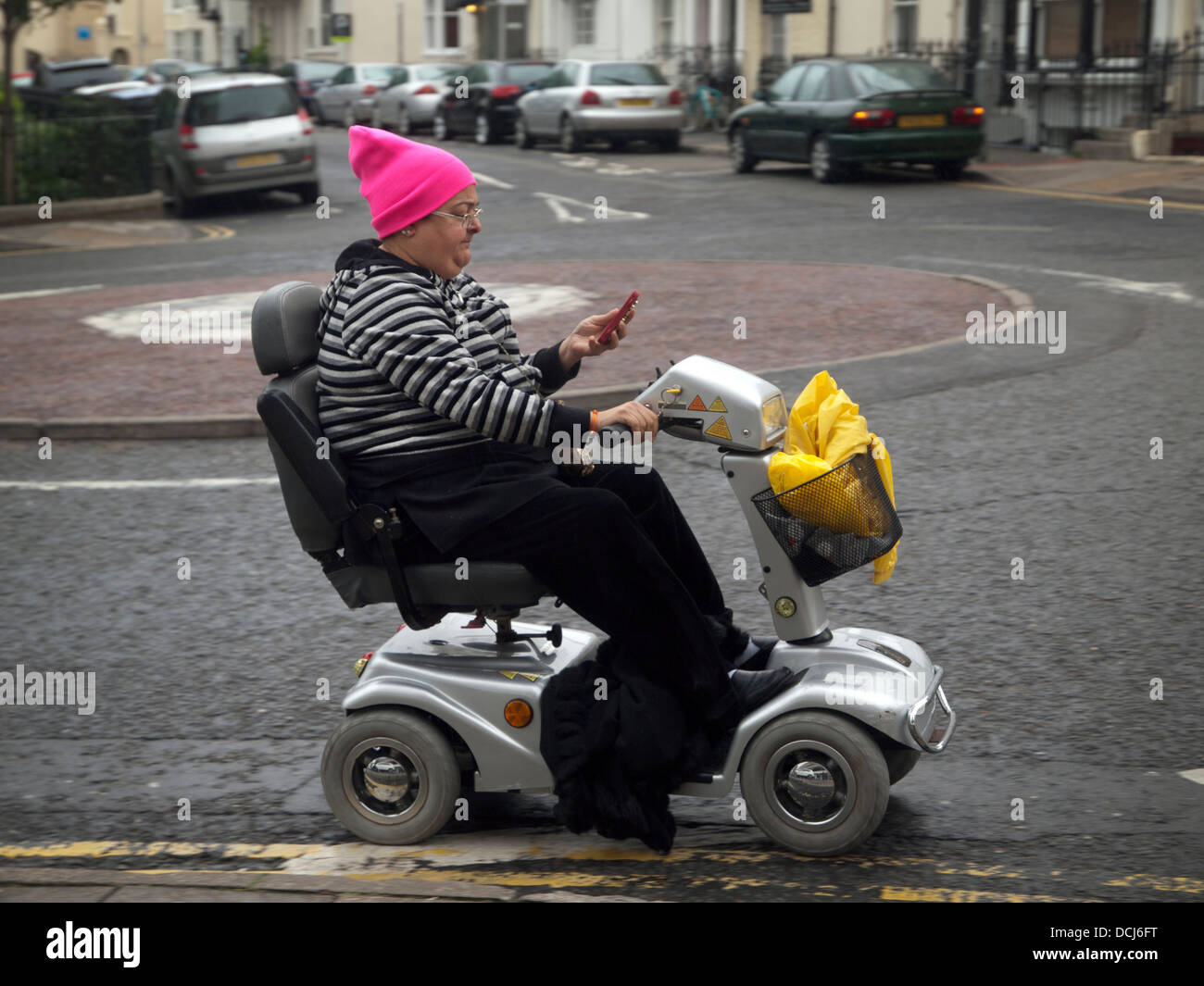 Alors qu'un fauteuil roulant motorisé une dame vérifie son téléphone Banque D'Images