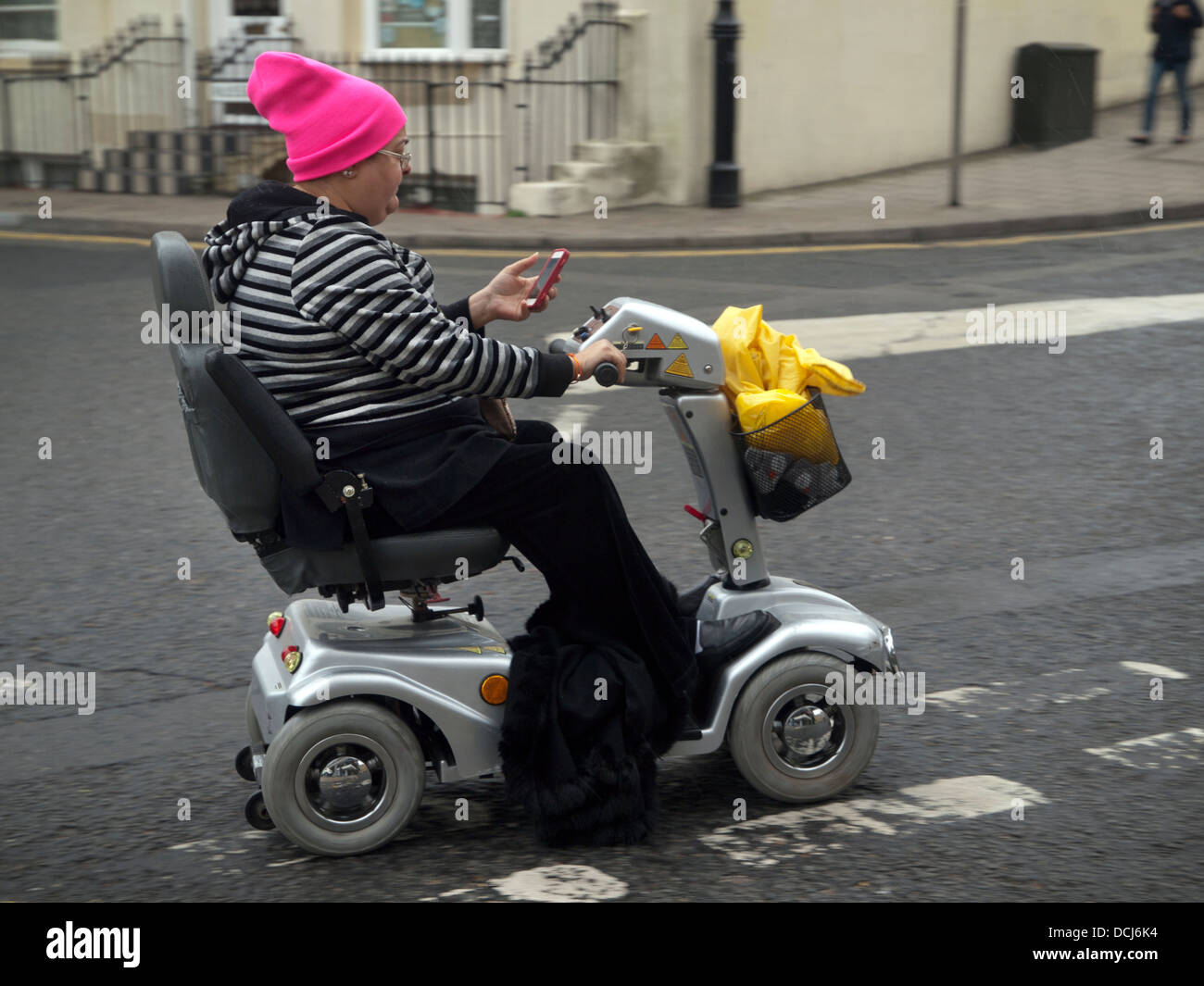 Alors qu'un fauteuil roulant motorisé une dame vérifie son téléphone Banque D'Images