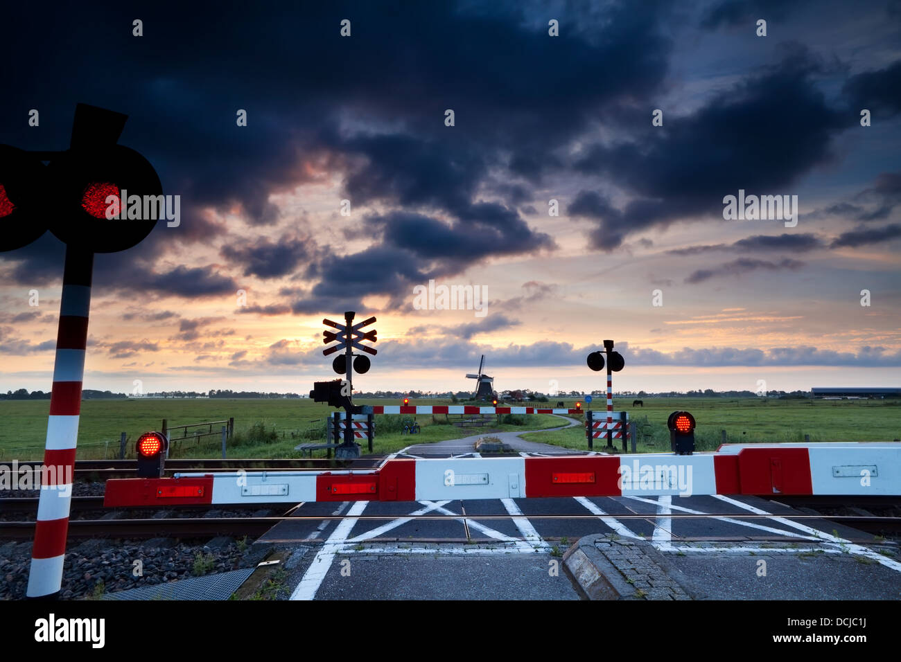 Passage à niveau fermé avec des signaux rouge au lever et au moulin Banque D'Images