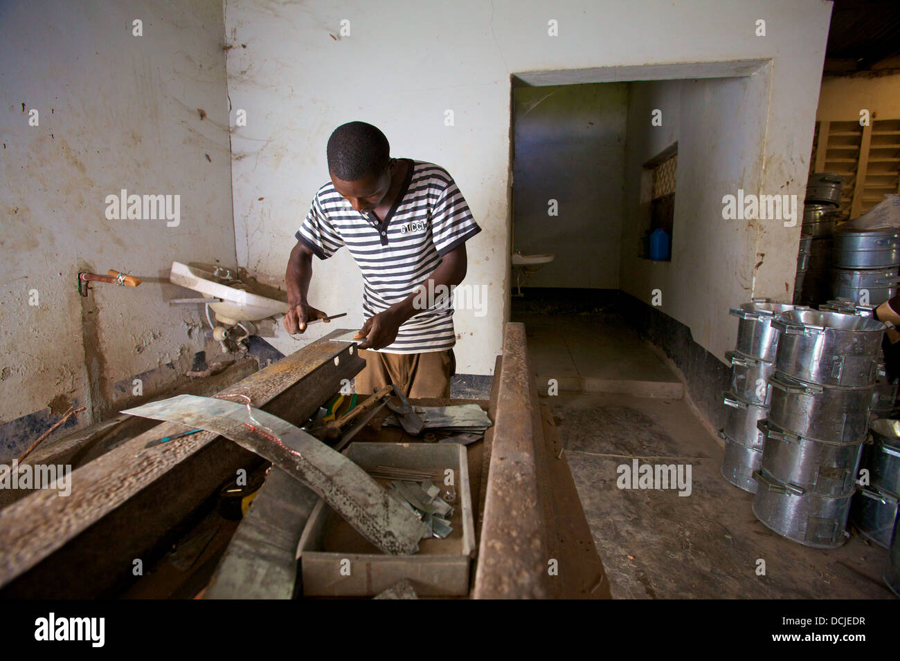 Artisan de la préparation des bandes métalliques pour la construction de fourneaux de cuisine d'Afrique, en Tanzanie. Banque D'Images