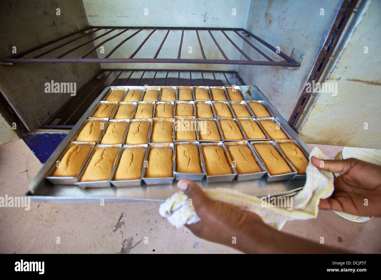 Femme tanzanienne dépose des petits pains d'un four de charbon à haute efficacité énergétique, en Tanzanie Banque D'Images