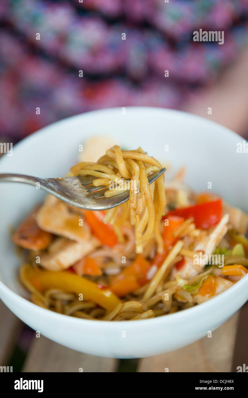 Sauté de poulet et nouilles chinoises, woman eating à partir d'un bol. Banque D'Images
