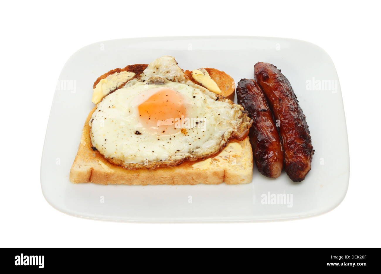 Saucisses et œufs frits sur toast sur une assiette blanche contre isolés Banque D'Images