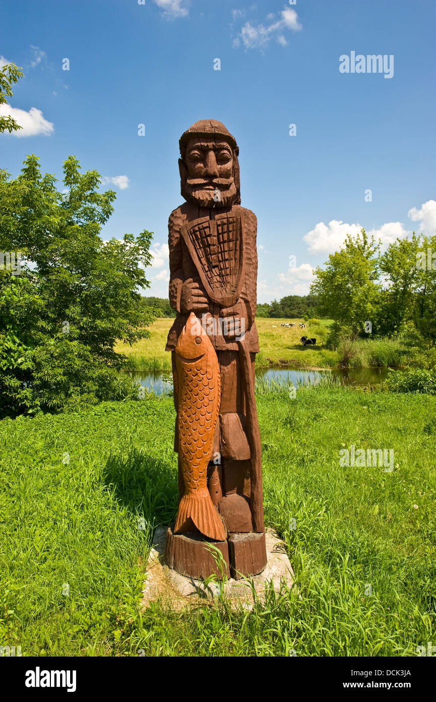 Sculpture en bois d'un pêcheur dans un village du nord-est de la Pologne. Banque D'Images