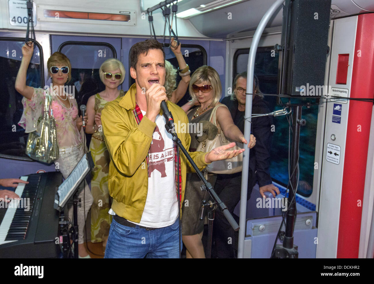 Hambourg, Allemagne. Août 19, 2013. Acteur de premier plan (Pfaff Luk avec microphone) et acteurs musicaux effectuer certaines parties de la nouvelle comédie musicale pendant un communiqué de date pour la nouvelle comédie musicale "ligne S1' dans un S-Bahn (réseau express régional) à Hambourg, Allemagne, 19 août 2013. L'Hamburg encore de fera la création à St Pauli Theatre le 08 septembre 2013. Photo : Georg Wendt/dpa/Alamy Live News Banque D'Images