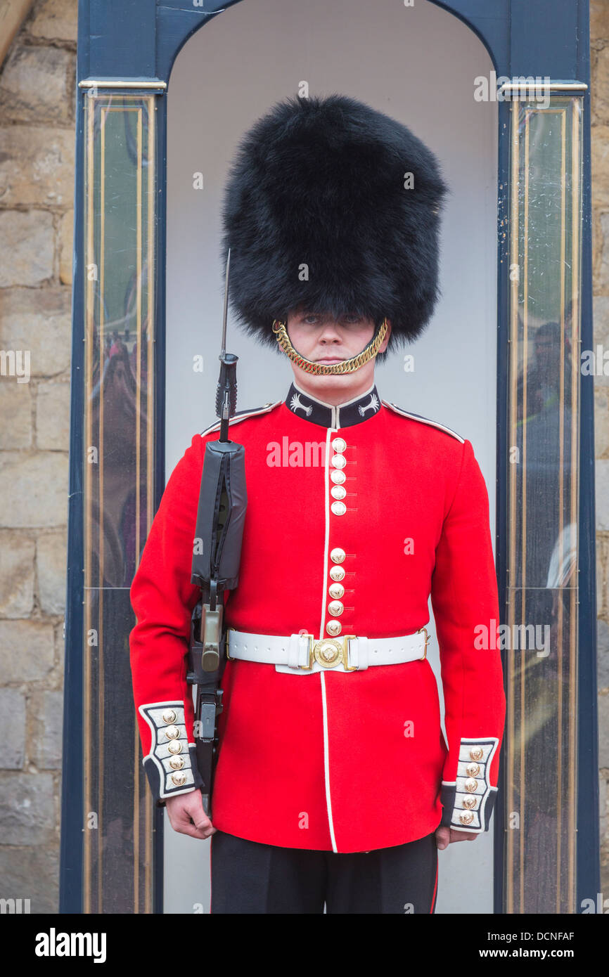 Soldat dans la garde de la Reine au château de Windsor, en Angleterre, se tenant à l'attention dans une guérite en uniforme rouge et noir traditionnel cap bearskin ou busby Banque D'Images