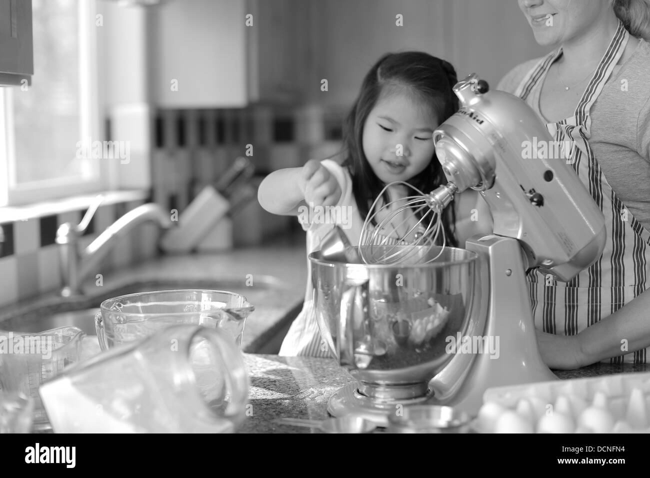 Jeune fille mère aidant à cuire dans la cuisine Banque D'Images